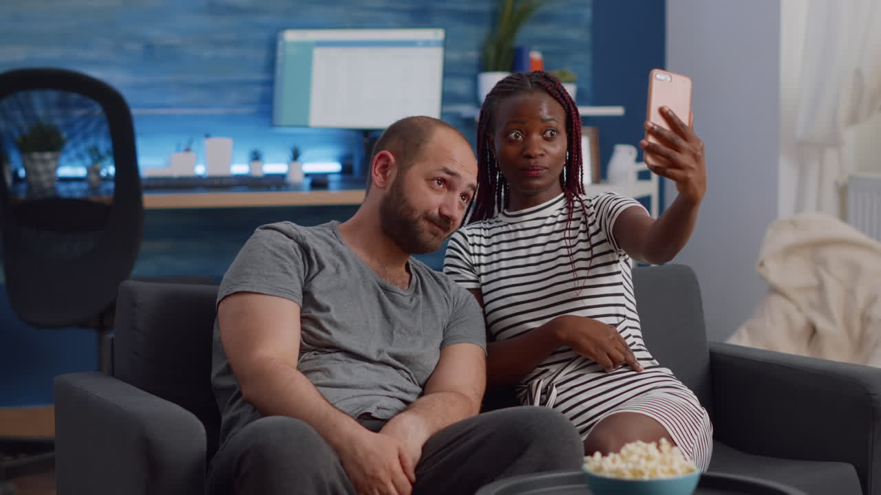 Casal interracial alegre tirando fotos com smartphone