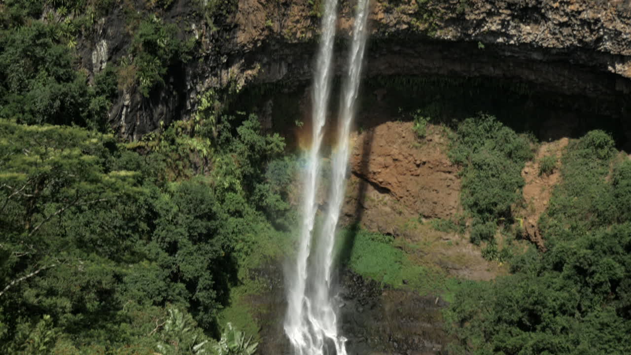 tiro inclinado hacia abajo de la corriente de agua de la cascada que cae con el arco iris en un día soleado