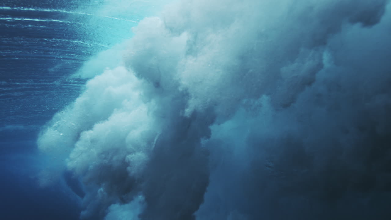 Dense underwater wave turbulence forming cloudlike foam and deep blue ocean texture