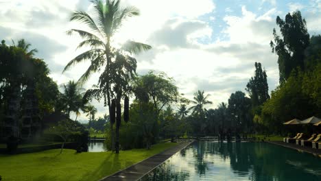 Zeitlupenaufnahme-Eines-Wunderschönen-Pools-Im-Morgengrauen-Auf-Bali,-Indonesien,-Mit-Blick-Auf-Den-Grünen-Garten-Mit-Bäumen-Und-Palmen-Während-Einer-Tollen-Reise