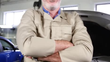 mecánico de pie con los brazos cruzados mientras atiende un motor de automóvil