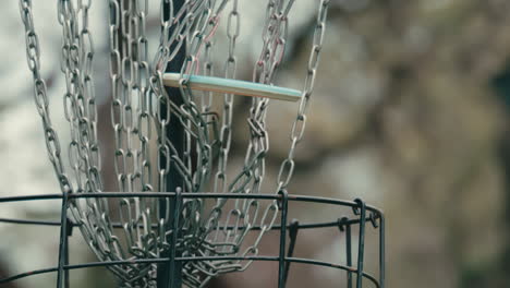 Disc golf frisbee hits chains and falls into basket in slow motion