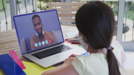 chica caucásica en chat de video portátil con máscara facial en casa