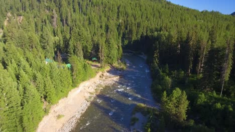 Toma-Aérea-Con-Vistas-A-Un-Impresionante-Río-Azul-Y-Luego-Se-Inclina-Hacia-Arriba-Para-Revelar-Una-Casa-Verde-Escondida-En-El-Bosque-Boreal-De-Canadá-En-Columbia-Británica