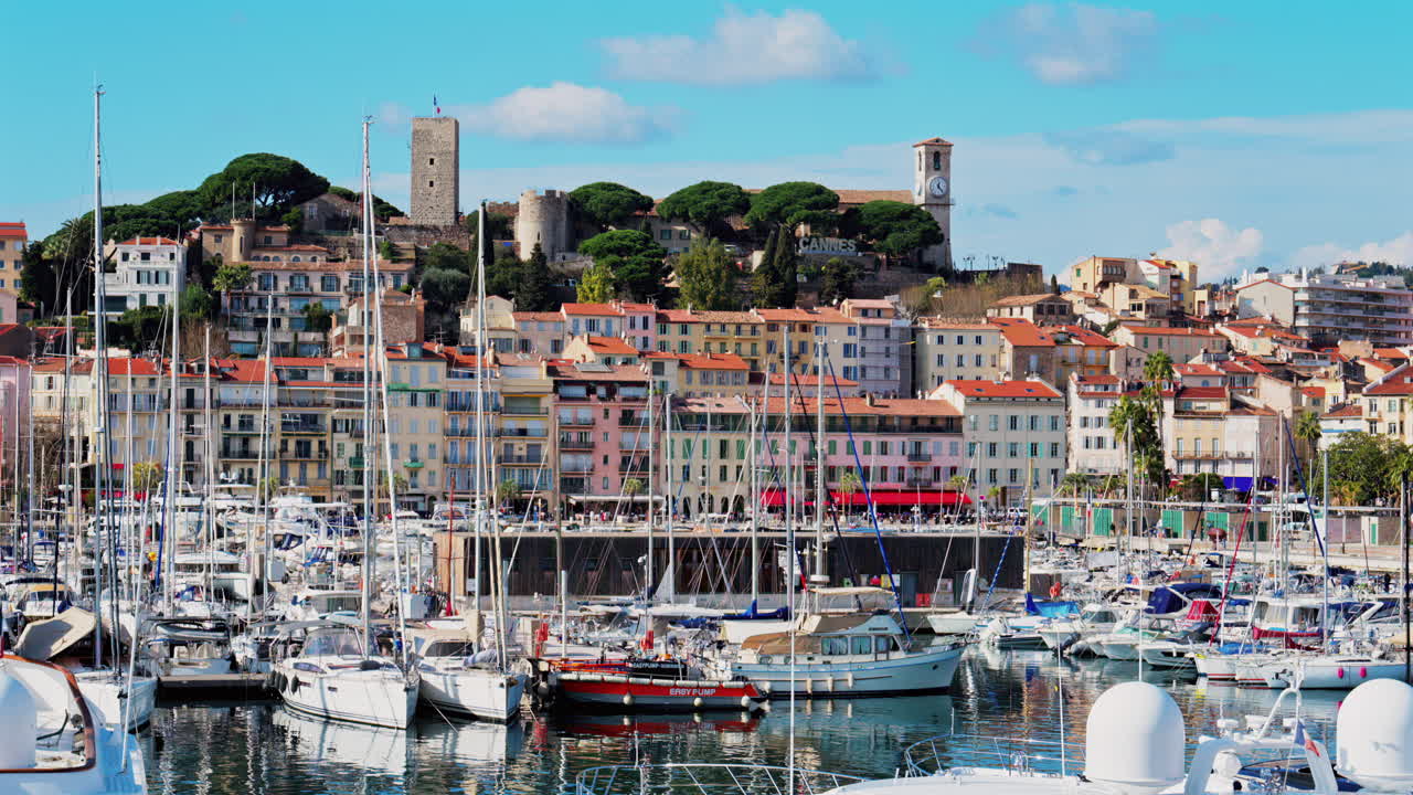 Cannes, France - February 10, 2025: Boats docked in the Cannes Marina with the colourful building of the city on the background