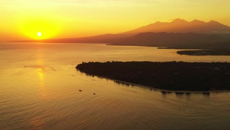 sun slowly dipping below the horizon across a large body of water with a small island and mountains in the background