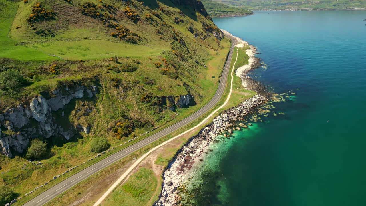 Wide, advancing aerial video of the green cliffs on the Causeway Coastal Route in County Antrim, Northern Ireland, UK, on a bright and sunny day. Filmed in 4K, 60FPS and with Rec709 color.