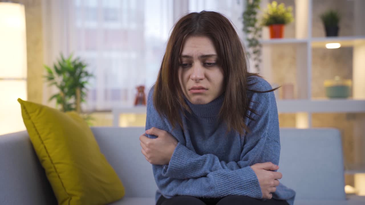 mujer joven triste sentada en el sofá sintiéndose infeliz, teniendo pensamientos desagradables, sufriendo debido a los problemas de la vida.