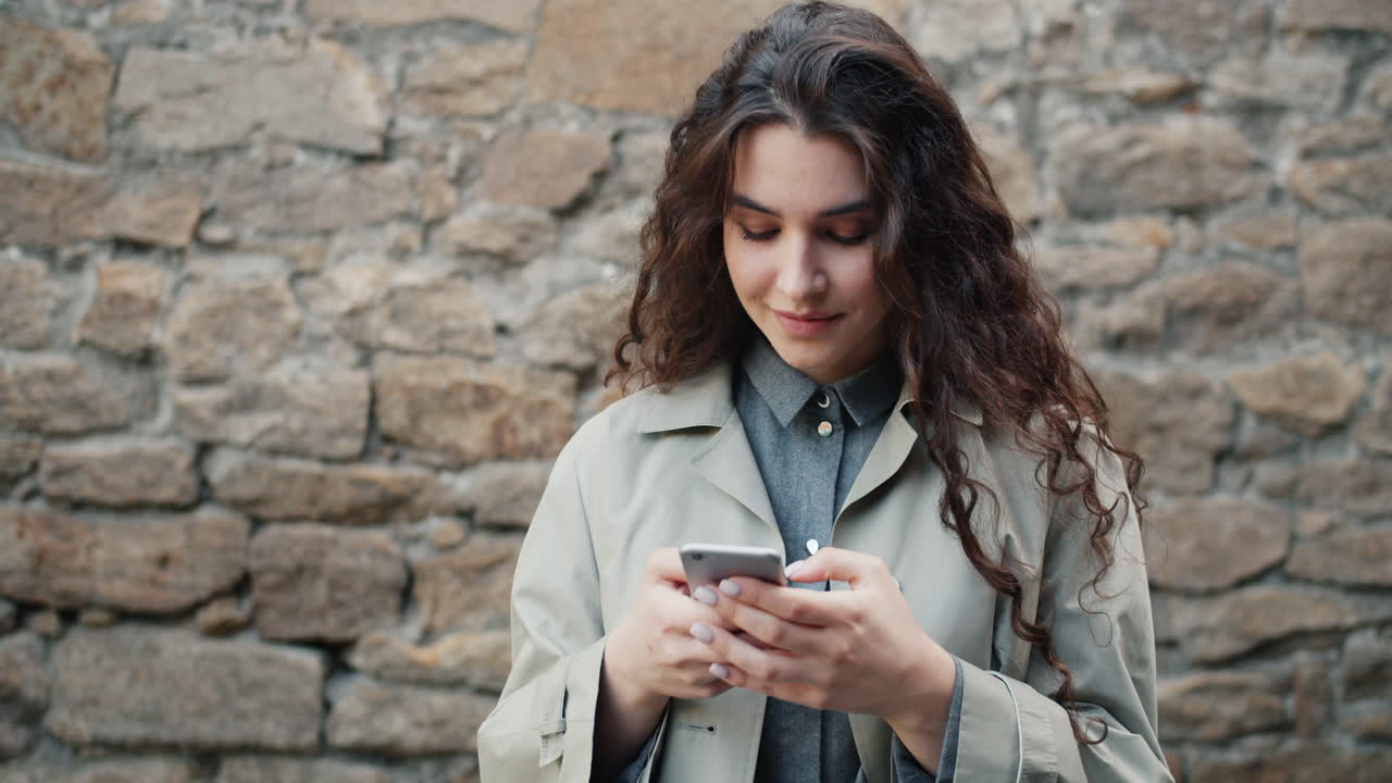 Donna che usa il telefono all'aperto vicino a un muro di pietra