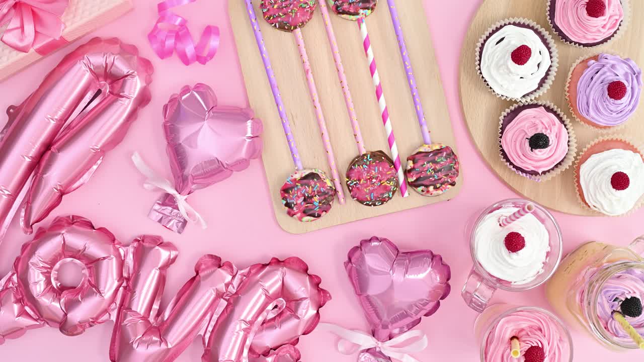 la mano de la mujer tomando postre dulce de tema rosa pastel con globos de san valentín y pasteles y pasteles. detenga el movimiento plano