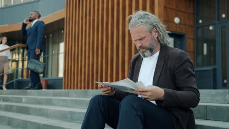 businessman reading documents on stairs