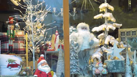 Santa-Claus,-Christmas-lights-and-decorations-behind-the-window-of-city-shop