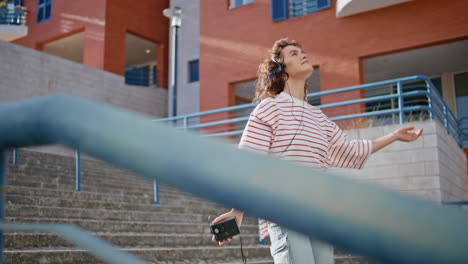 auriculares adolescente bailando escalera de la calle en un día de verano. chica escuchando música