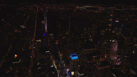 Vista-Aérea-Del-Paisaje-Urbano-Nocturno.-Altos-Edificios-Iluminados-Y-Largas-Calles-Rectas-Y-Avenidas-Con-Tráfico.-Manhattan,-Ciudad-De-Nueva-York,-Estados-Unidos