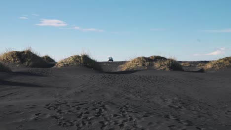 car parked between black sand beach dunes, other drives away, iceland