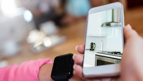 person holding smartphone with modern kitchen interiors displayed on screen