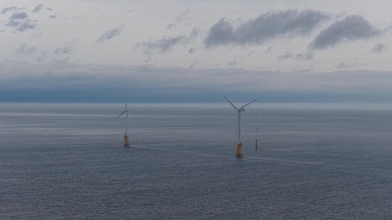 Horisontal luftudsigt over havvindmøller nær Gimnyeong Strand på Jeju Ø, Sydkorea, med et stabilt kamera over havet