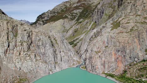 Aerial-Flyover-of-Turquoise-Trift-Lake-with-Triftbrucke-and-Glacier-View