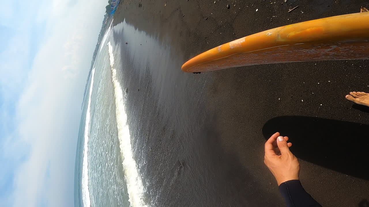 pov gopro, surfista sosteniendo tabla de surf caminando en la playa