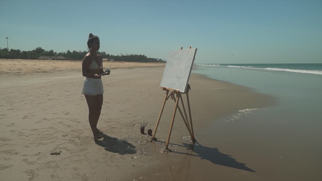Young artist painting on a sunny beach, elegant female paints artistic expression outdoors