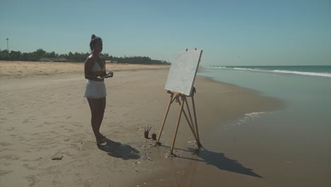 young artist painting on a sunny beach, elegant female paints artistic expression outdoors