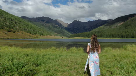 aerial cinematic drone following female women model actress playing with cute dress walking toward piney lake ranch vail beaver creek colorado gore range mountain landscape summer afternoon rain sun