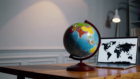 globe and laptop on a wooden desk
