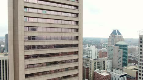 rising aerial of brown gray concrete government office building skyscraper with reflective glass windows in downtown urban usa city