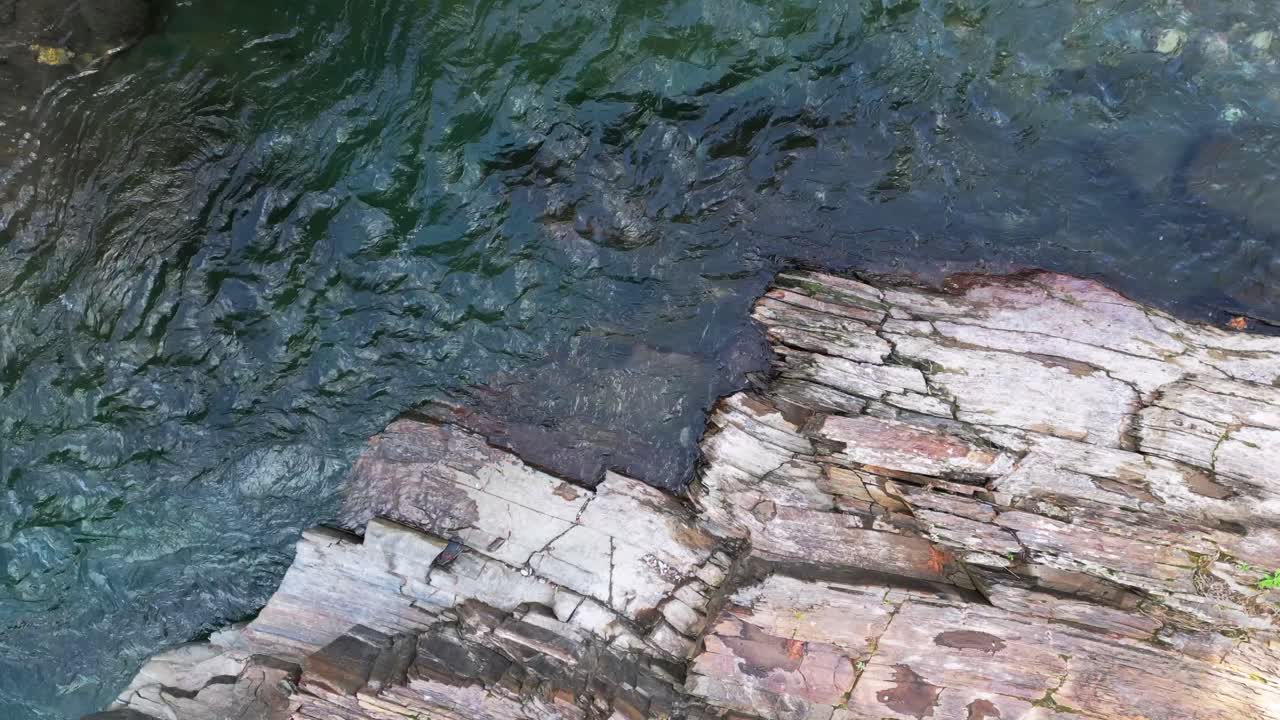 Vista ravvicinata da drone dell'acqua del fiume che scorre oltre formazioni rocciose stratificate in un'area balneabile naturale in Estremadura, Spagna. Paesaggio di acqua dolce panoramico e concetto di viaggio estivo.