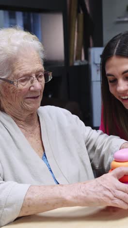 elderly woman playing with stacking rings with a young woman