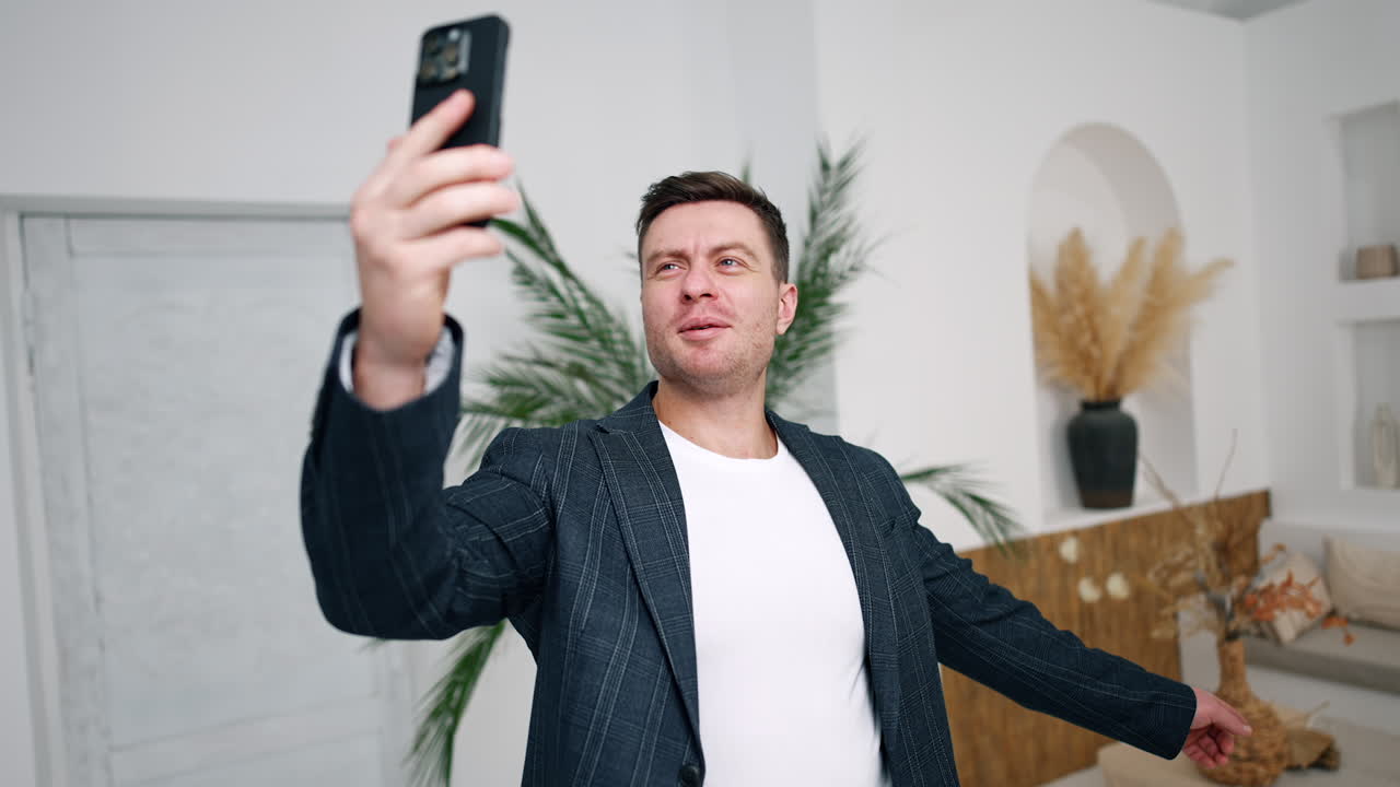 Athletic Caucasian man having video conversation. Man points at something behind him and turns to the sides.