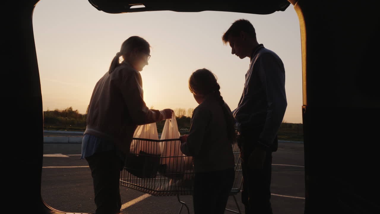 가족은 자동차 부츠에 슈퍼마켓에서 쇼핑백을 넣습니다.