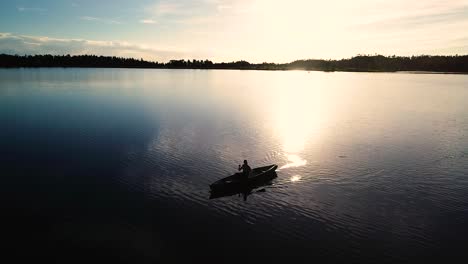 Hermoso-Amanecer-De-Colorado-En-Un-Lago-Con-Una-Silueta-De-Una-Canoa-Contra-El-Sol-Naciente