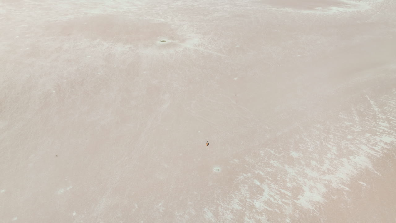 vista aérea de una mujer caminando sobre un lago salado en türkiye