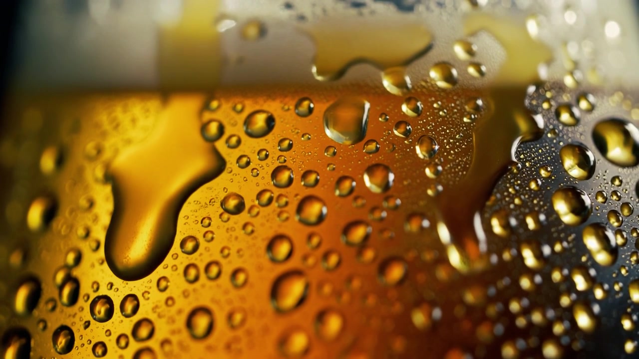 Condensa che cola lungo un bicchiere freddo di birra dorata