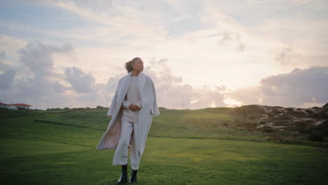 Gorgeous-woman-walking-field-in-stylish-coat.-Thoughtful-african-american-dream