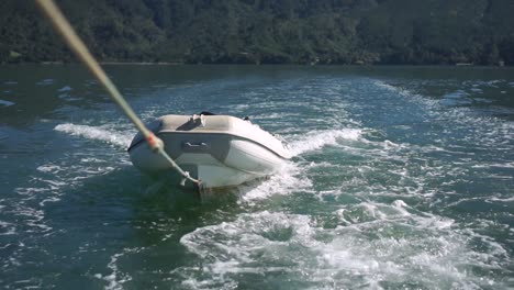 slowmo - bote inflable remolcado por una cuerda detrás de un barco en el océano de nueva zelanda