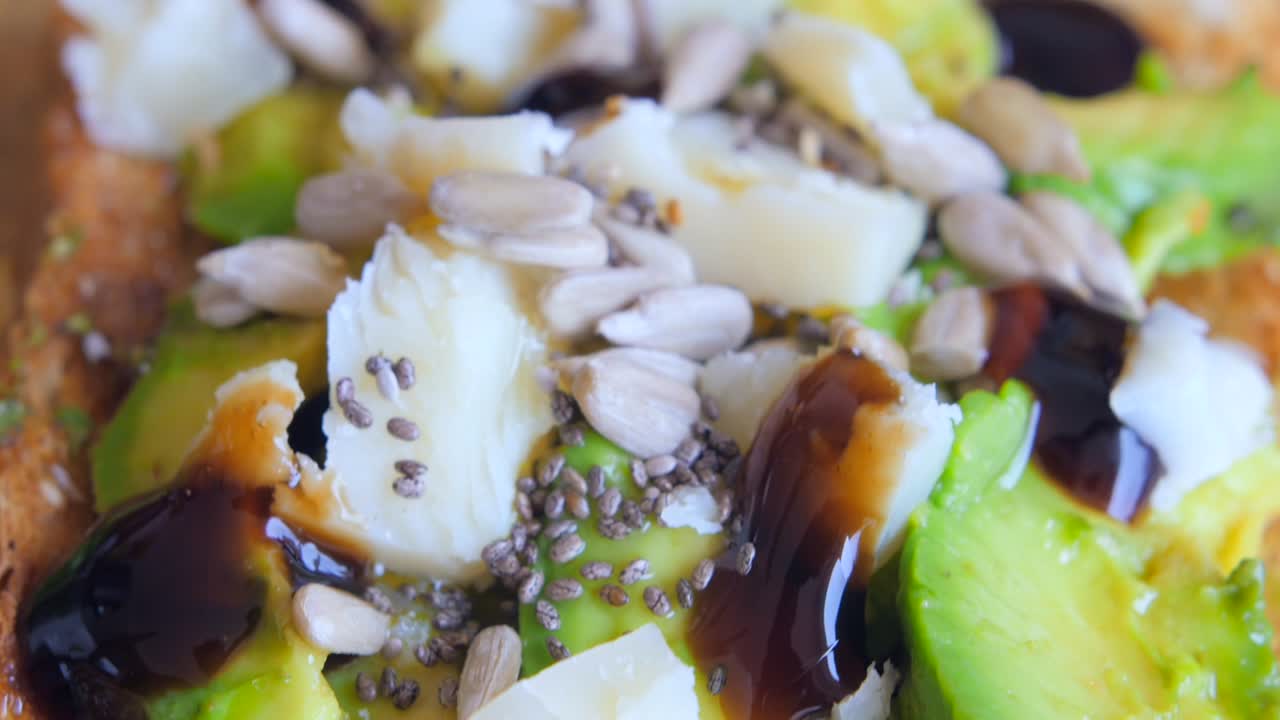 아침 식사로 견과류와 파마산 치즈를 곁들인 맛있는 아보카도 토스트의 매크로 샷