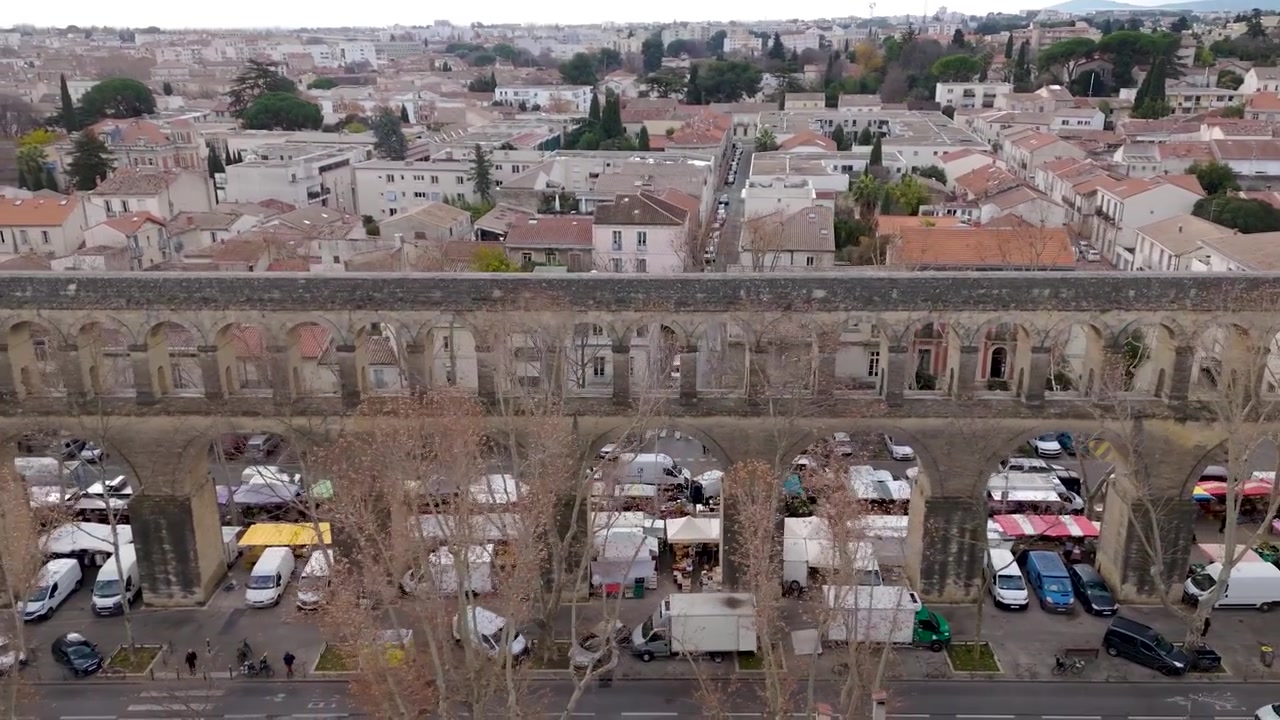 L'Acquedotto di Saint Clement domina bancarelle del mercato e case a Montpellier, Francia, ripresa aerea media con carrellata a sinistra