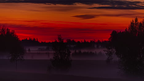 vibrant dark red color sky of sunrise and misty rural landscape, fusion time lapse