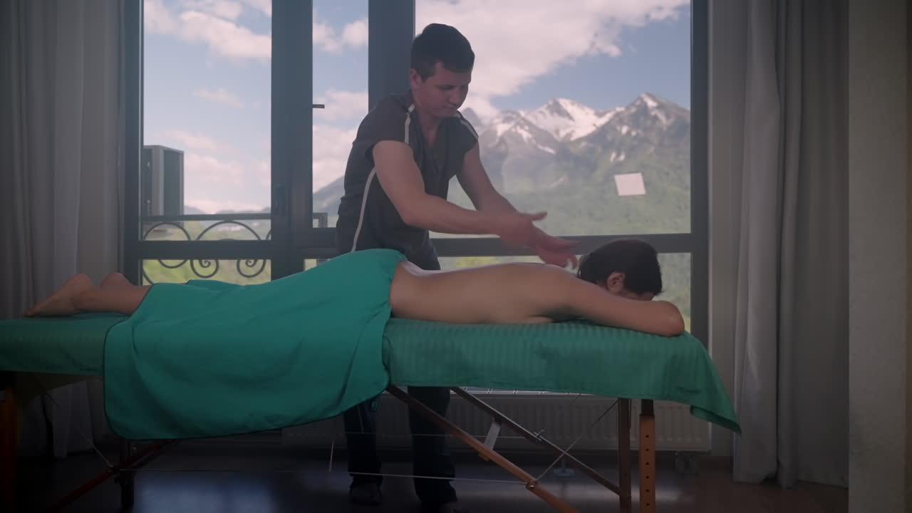 치료사 에 의해 등 마사지 를 받는 여자, 배경 에 아름다운 산 전망