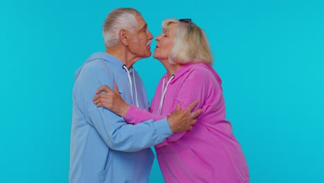 Romantic-senior-couple-man-woman-grandparents-making-lots-of-kisses-looking-at-camera-and-smiling