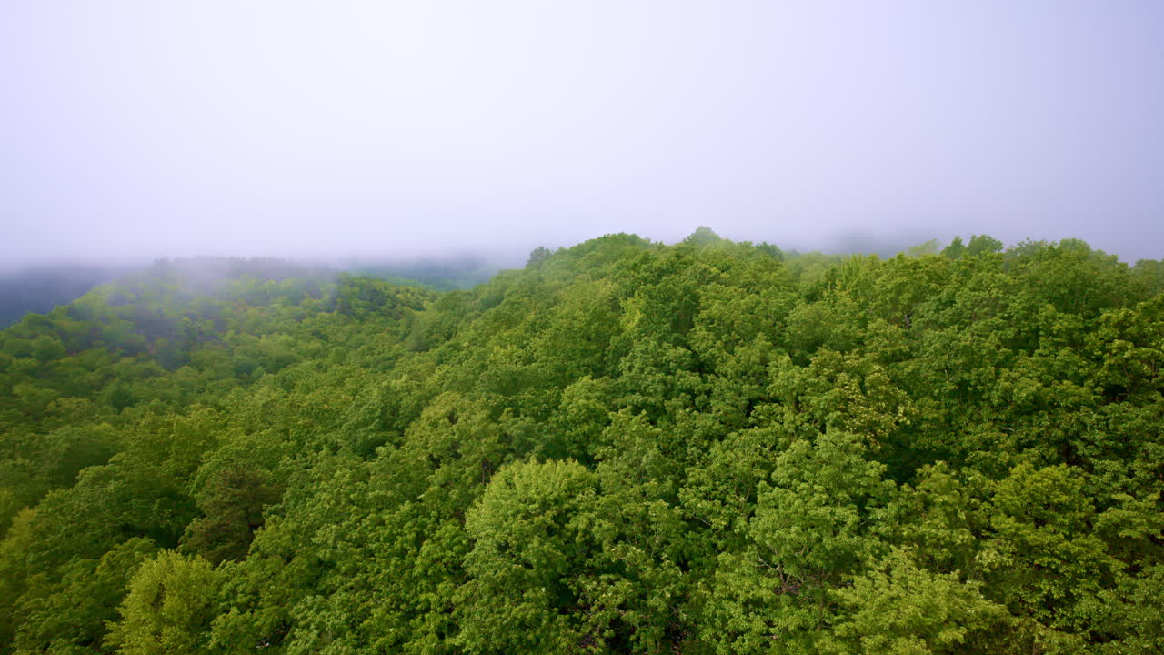 Cinematic drone glide above hazy, foggy mountain scenery