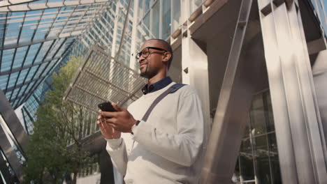 african american businessman walking through city using smart phone