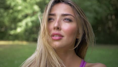 pretty blonde woman in soft light sits outside in a park