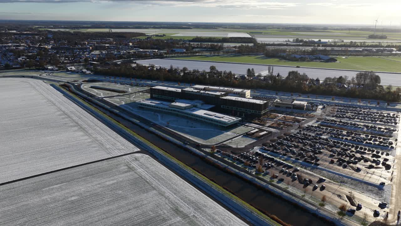 Aerial drone video footage of the modern Ommelander Hospital in Scheemda, Groningen, in a winter landscape. The facility is a sustainable, energy-efficient, and welcoming healthcare building