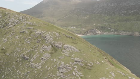 Drone-Volando-Sobre-Una-Colina-Cubierta-De-Follaje-Que-Revela-La-Playa-De-Arena-Blanca-De-Keem-En-La-Costa-Del-Océano-Atlántico-En-La-Isla-De-Achill,-Condado-De-Mayo,-Irlanda