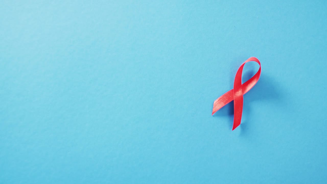Vidéo d'un ruban rouge de sensibilisation au VIH ou au SIDA sur fond bleu avec espace pour le texte