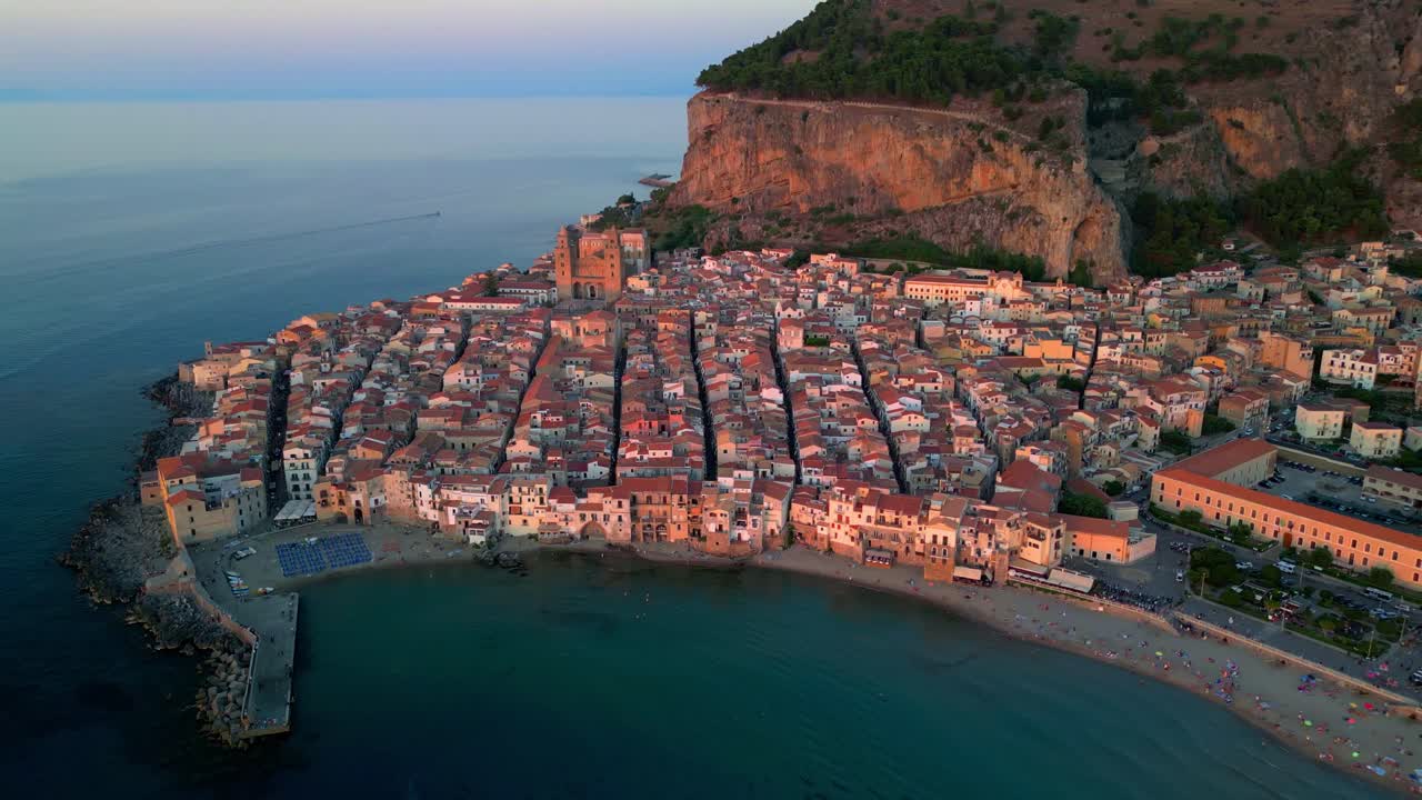 Panorama aereo ad alta quota di Cefalù che cattura il contrasto tra l'architettura medievale e il mare aperto