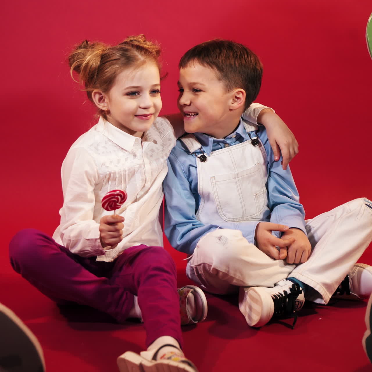 Due bambini. Un bambino e una bambina con un grande lecca-lecca. Ritratto in studio su sfondo rosso. Video quadrato